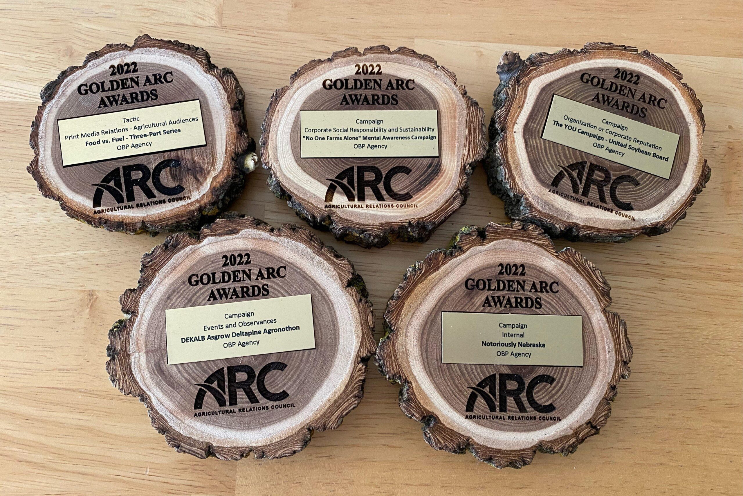 Five Golden ARC awards sitting on a wooden table.